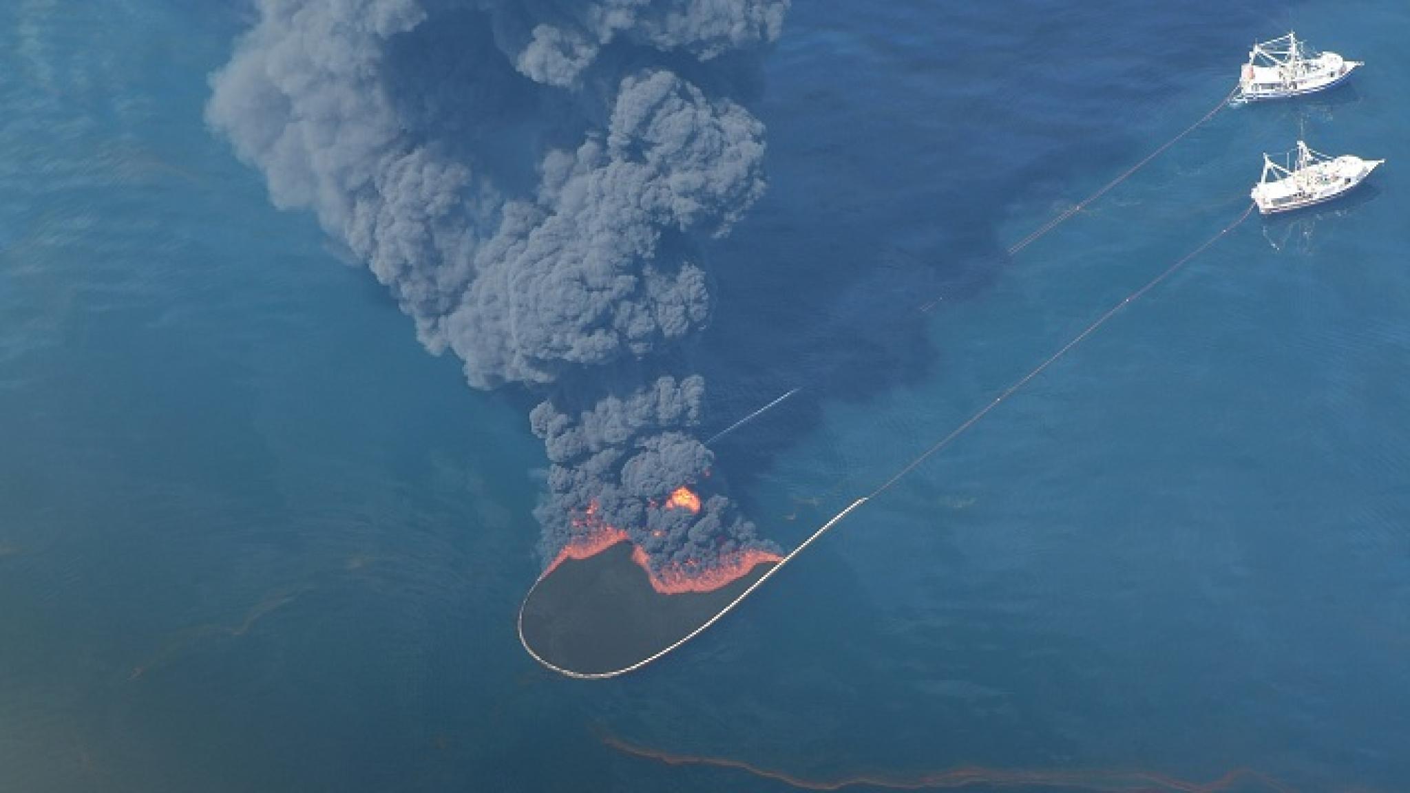 Photo of boats operating floating booms to contain burning oil spill, taken from U.S. Environmental Protection Agency's aircraft. Image is from Wikimedia Commons and is public domain as a work of the U.S. federal government. Photo of boats operating floating booms to contain burning oil spill, taken from U.S. Environmental Protection Agency's aircraft. Image is from Wikimedia Commons and is public domain as a work of the U.S. federal government.