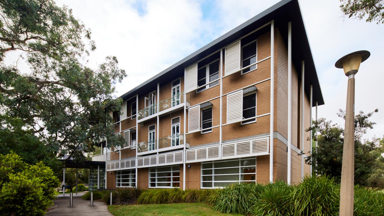 RegNet Building exterior - 3 floor building with white shutters surrounded by a path, trees and grass