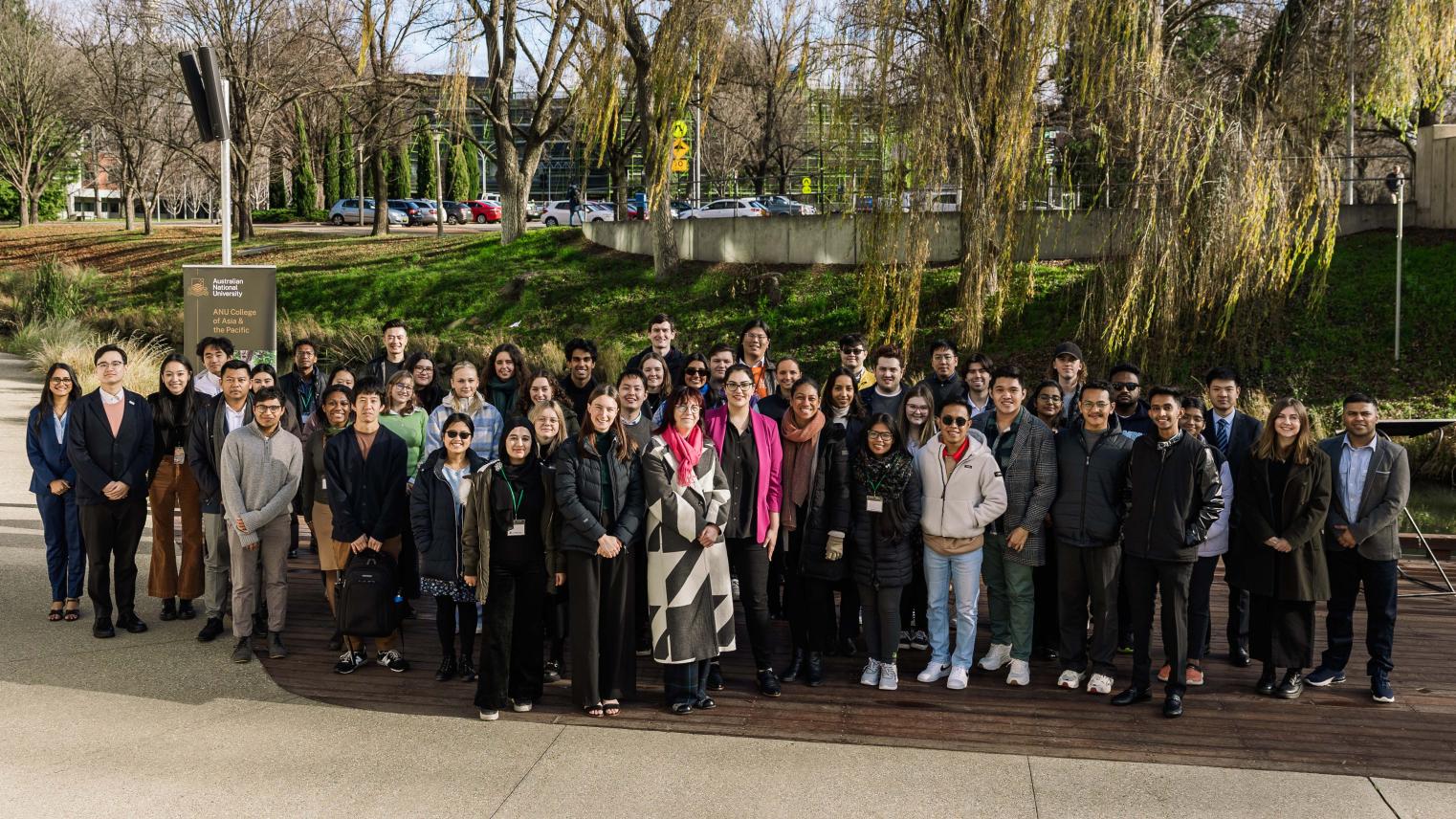 Asia Pacific Week delegates, panellists and organising committee members standing in front of trees for a group photo
