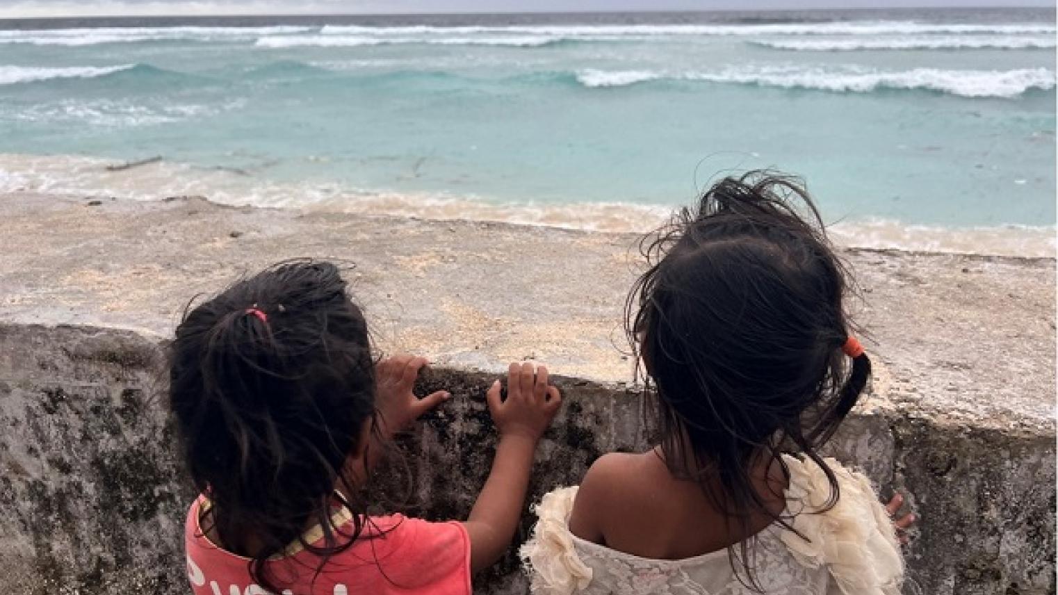 Photo of children looking out at the ocean from a sea wall, Kiribati, illustrating the existential threat posed by rising seas in the Anthropocene; supplied by the speaker
