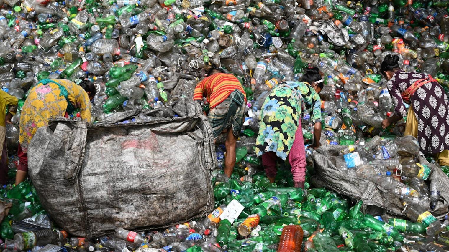 Image of people working on plastic bottles in a scrapyard by Mumtahina Tanni, free to use under pexels licence.