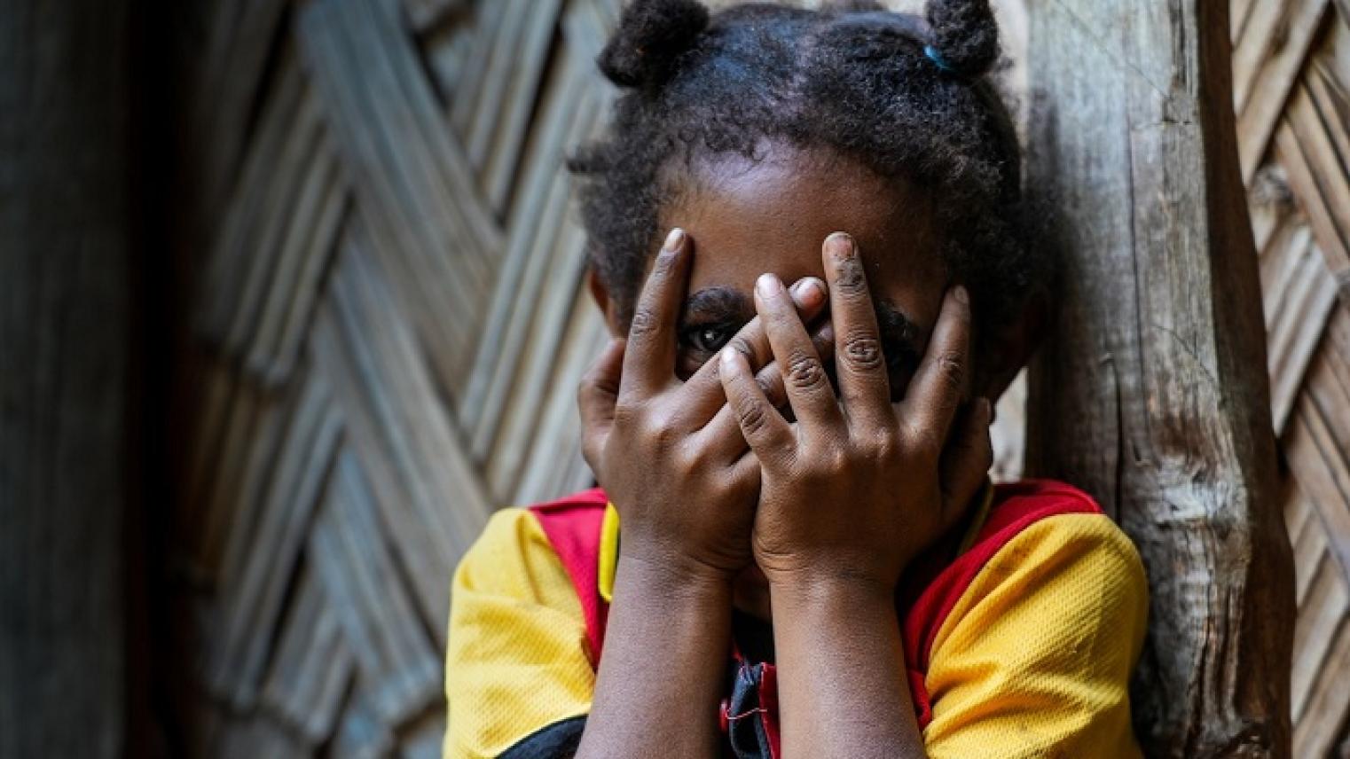 Photo of a young girl whose family members have been accused of sorcery hides her face in the settlements outside Goroka, Papua New Guinea, by Adam Browne.